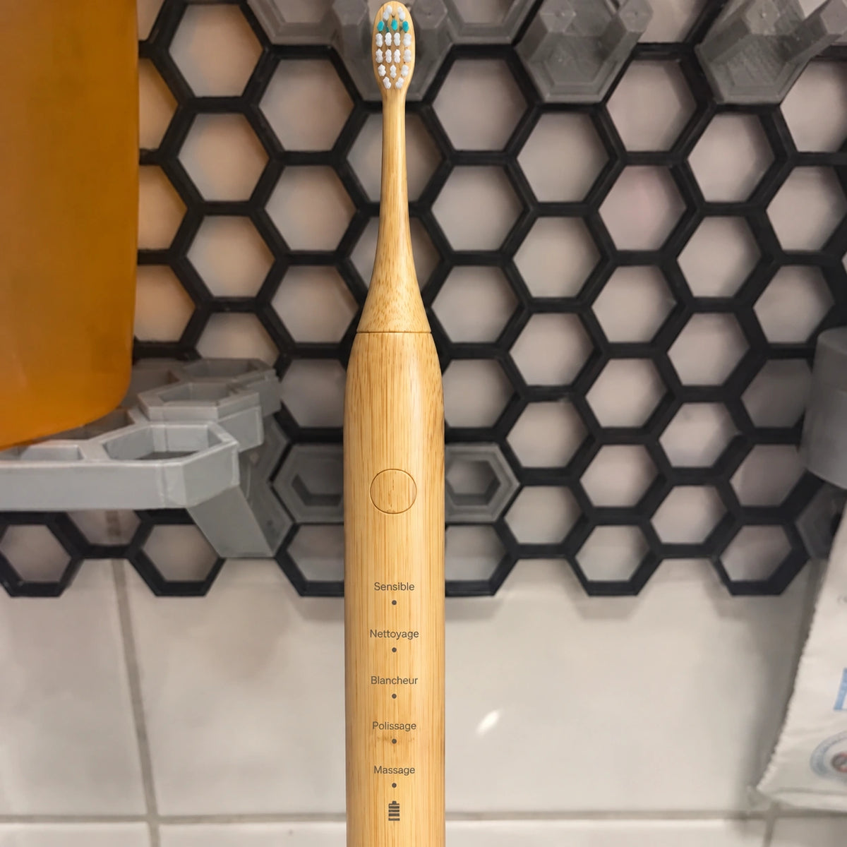 Brosse sonique en bambou devant des carreaux hexagonaux